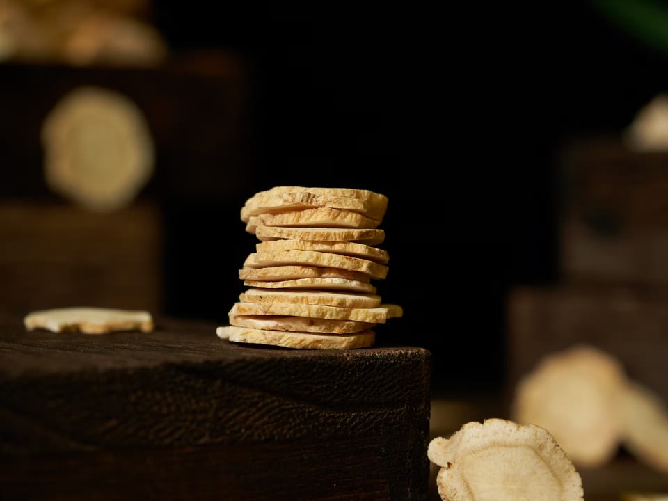Stack of dried ginger slices on a rustic surface.