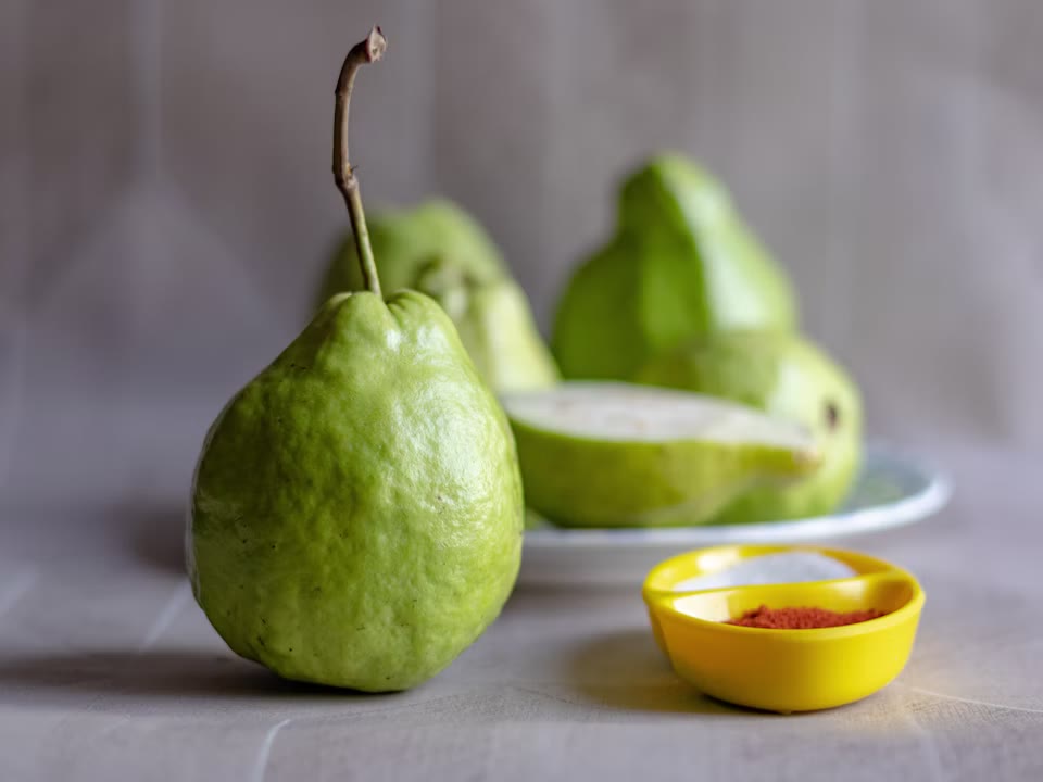 Fresh green guavas arranged on a plate.
