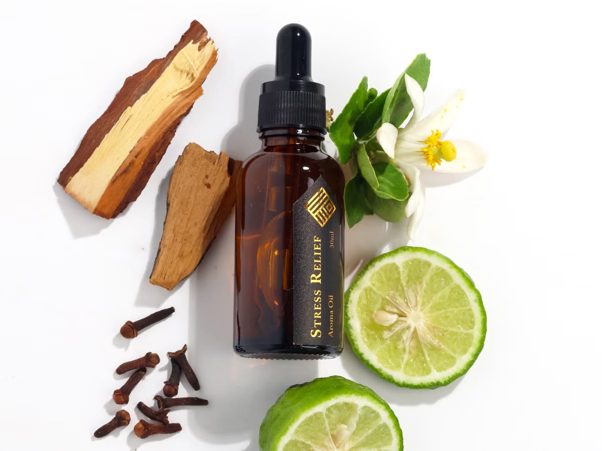 Amber essential-oil bottle beside sliced lime and whole spices.