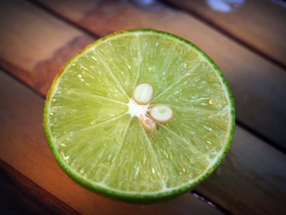 Halved lime showing pale seeds and green pulp on wood.